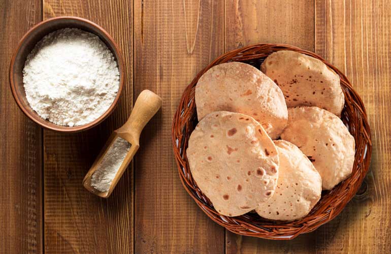 Two wooden bowl with flour in one and Muligrain Atta in the other