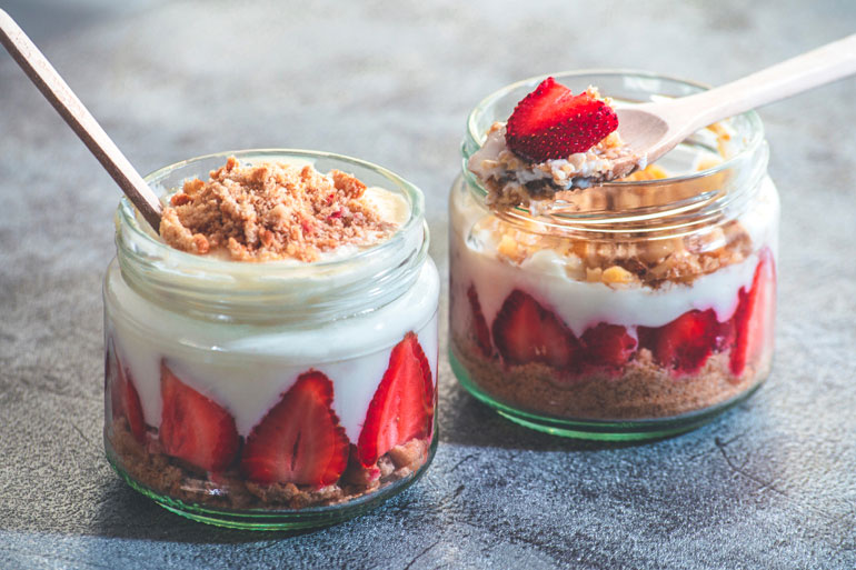 Two Trifle-Puddings in cups with spoons and strawberries