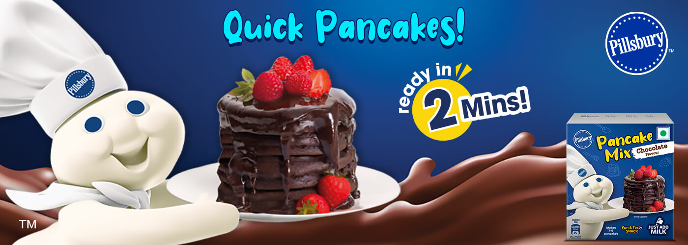 Doughboy holding a plate of Chocolate Pancakes with the text, "Quick Pancakes, ready in 2 minutes!" in the background. A front facing pack of Pancake Mix in the bottom corner.